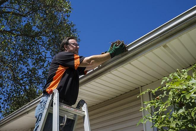 worker fixing a broken gutter on a house in Alpaugh